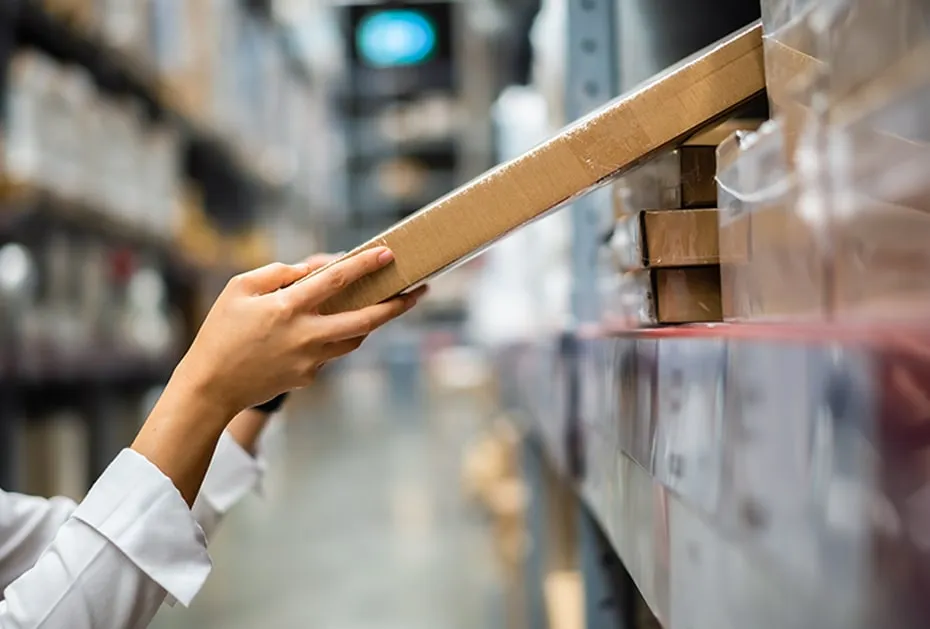 Mano retirando una caja de una estantería del almacén
